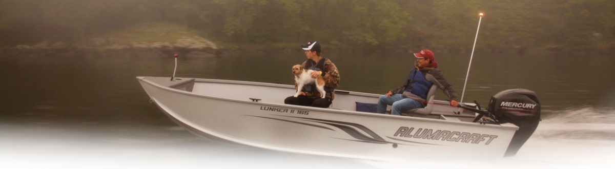 2017 two men and a dog in their boat at a lake.